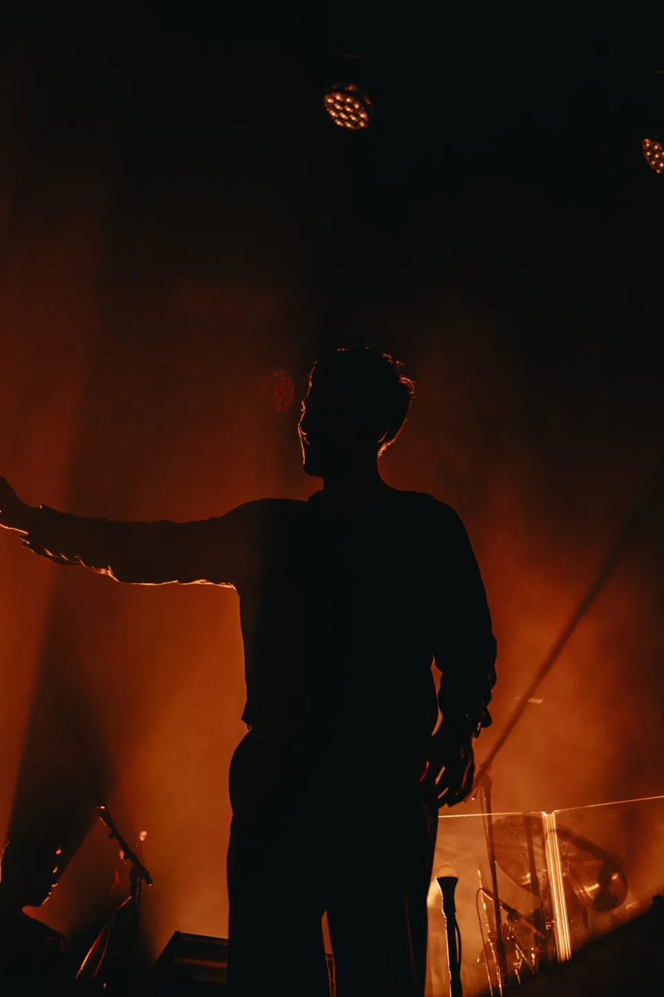 Silhouette of a performer outlined by deep orange backlight.