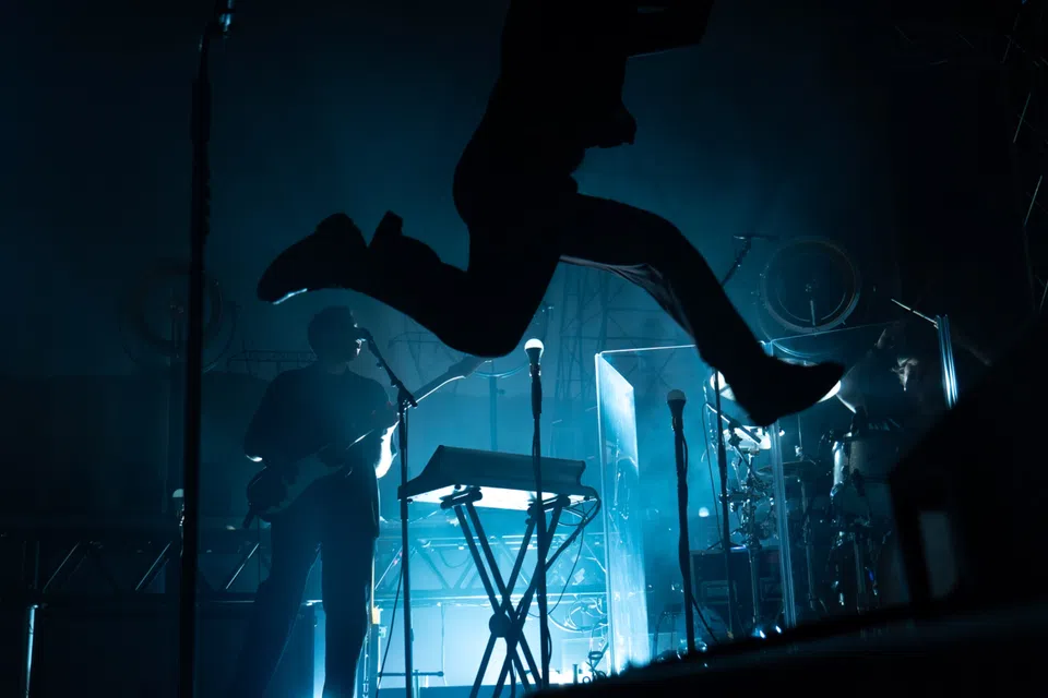 Performer in motion on a blue-lit stage.