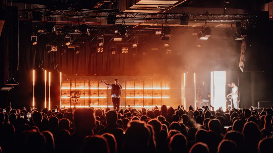 Wide orange-lit concert stage above a dense audience.